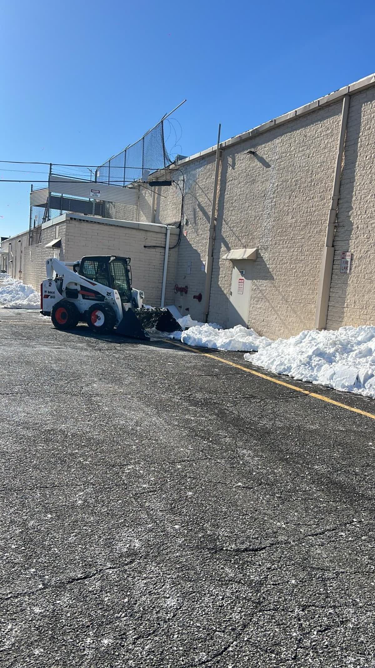 Skid steer loader pushing snow away from a commercial building in Philadelphia, PA